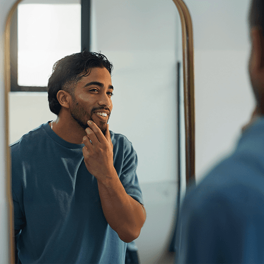 confidence-happy-man-bathroom-check-skincare-grooming-facial-results-home-dermatology-reflection-person-with-smile-hygiene-wellness-cleaning-morning-routine 1_p.png